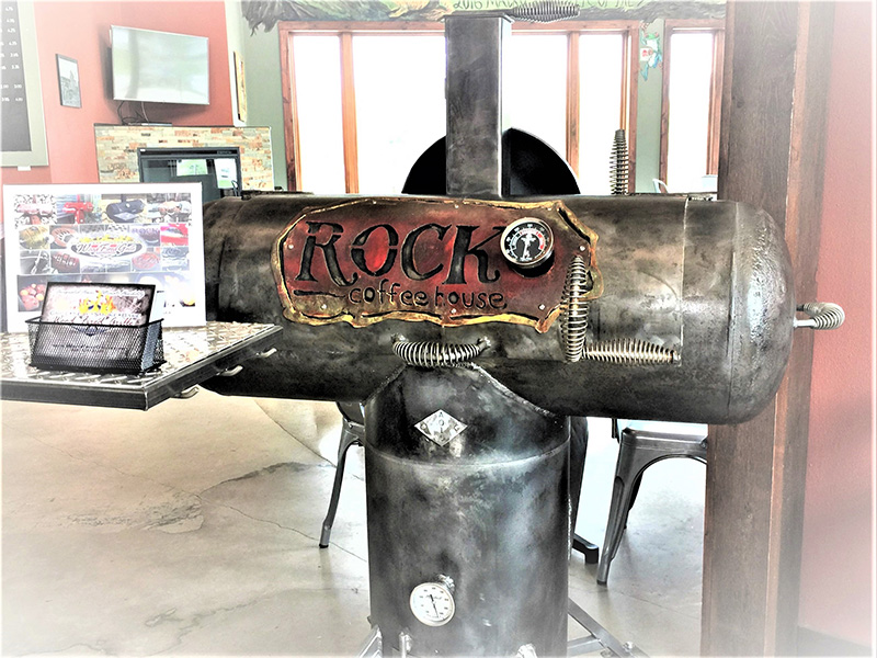 T-shaped gunmetal-color grill w/ cover art Rock Coffee House. Background coffee shop counter.