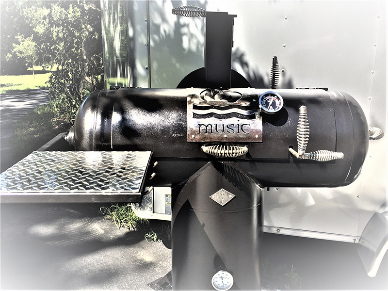 T-shaped black grill w/ silver-color cover art flames, over water, over Music. Background white trailer.