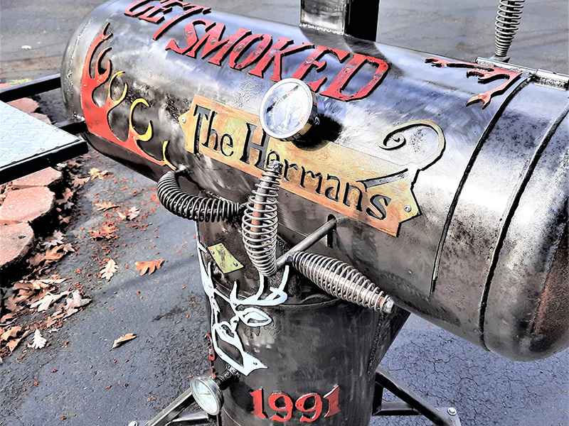 Gun metal colored grill with artwork Get Smoked The Hermans.