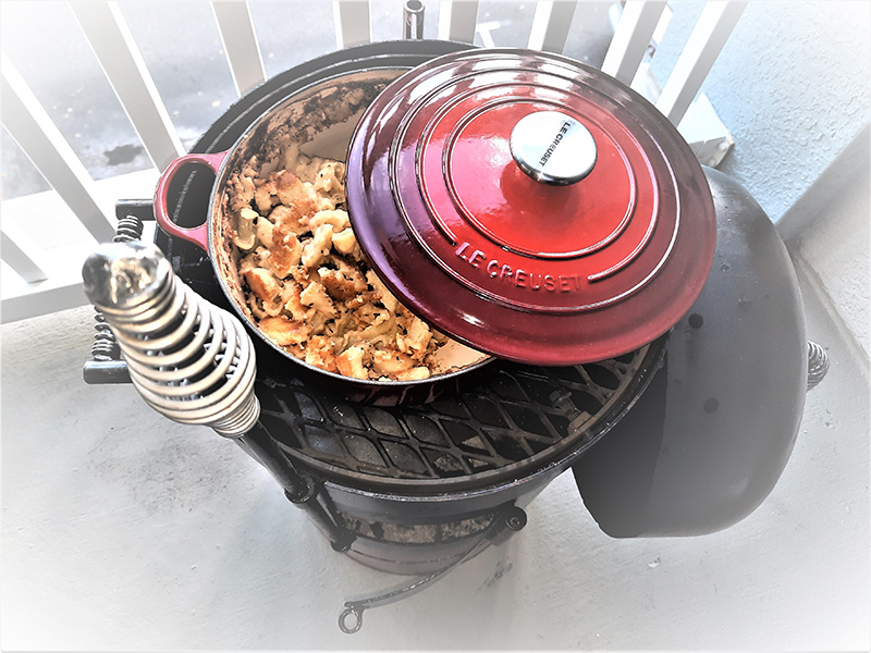 Top view of a Bullet grill with a pot of stew cooking on the grate.