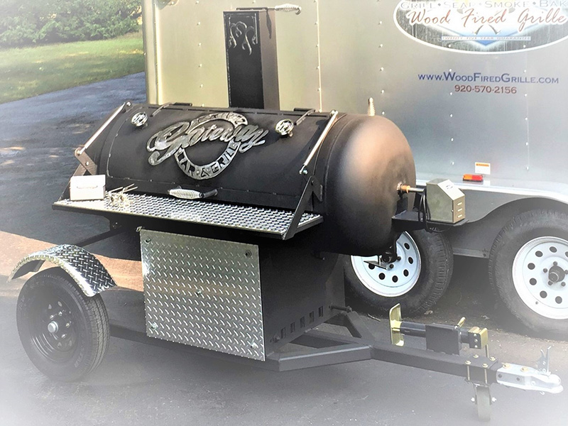 Black T-shaped Woodfired Grille mounted on a trailer and silver cover art saying Gateway Bar & Grill