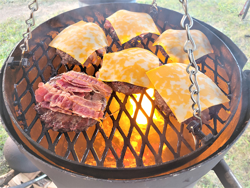 Bullet grill with cheeseburger and bacon burgers cooking.