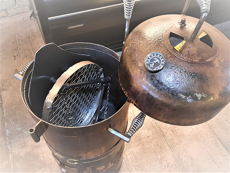 Rust colored Bullet Grill with hanging grill grate