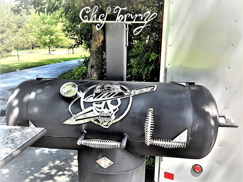 T-shaped black grill with silver artwork of skull wearing fedora and dagger