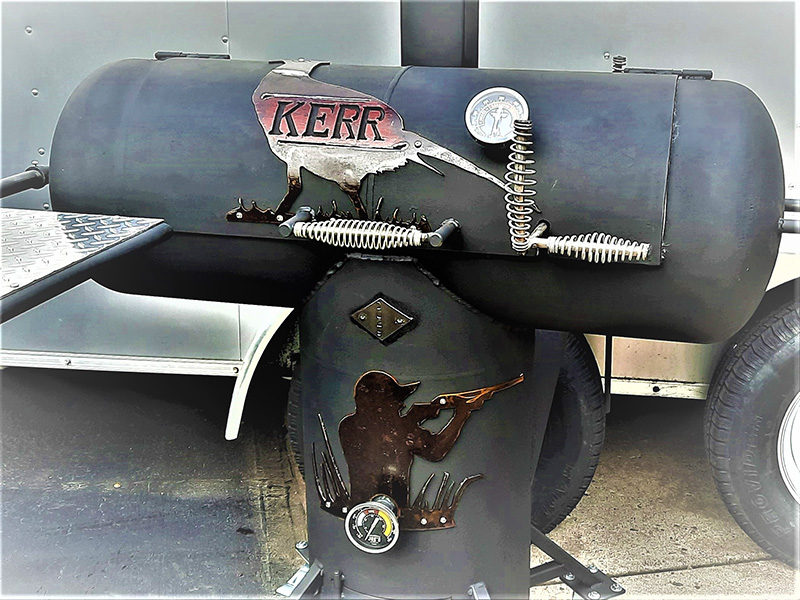 T-shaped black grill with silver bird with Kerr in center and rust colored hunter with rifle below artwork