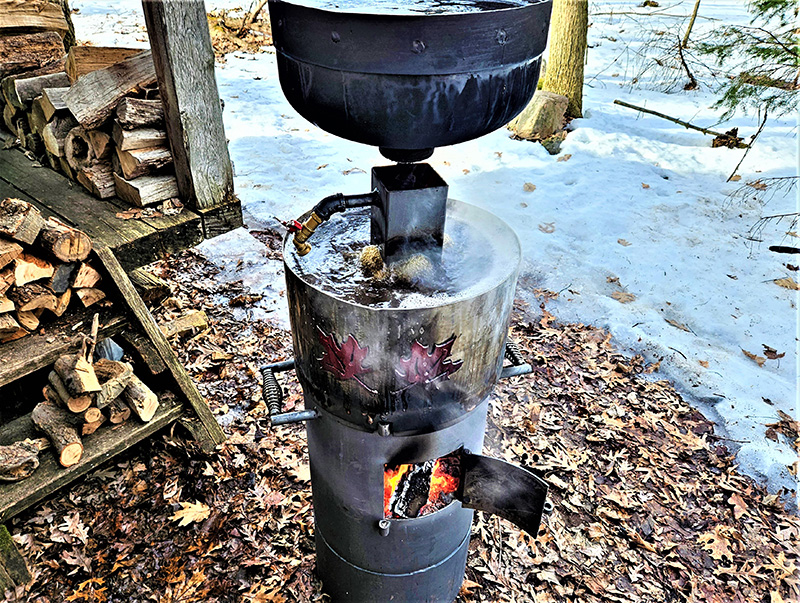 bullet-shaped black maple syrup boiler with red maple leaves artwork