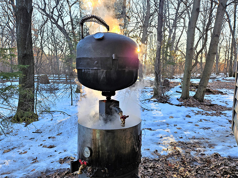 bullet-shaped black maple syrup boiler with red maple leaves artwork