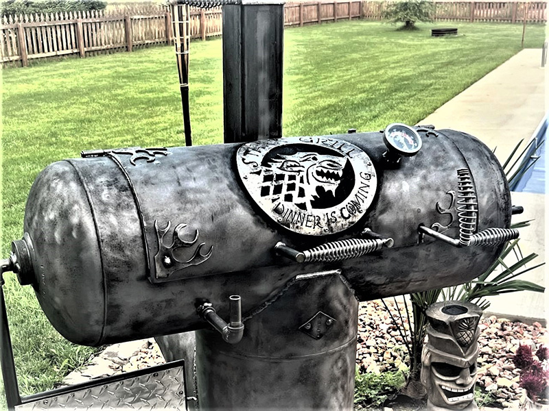 Gun-metal colored T-shaped grill with wolf head artwork and writing Dinner is Coming