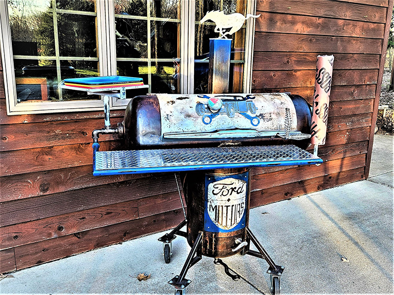 Large black and silver T-shaped grill with large diamond pattern shelf in front. Artwork antique car with crossed wrenches