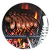 Close-up of sausages cooking on a grate over wood fire on a WoodFiredGrille